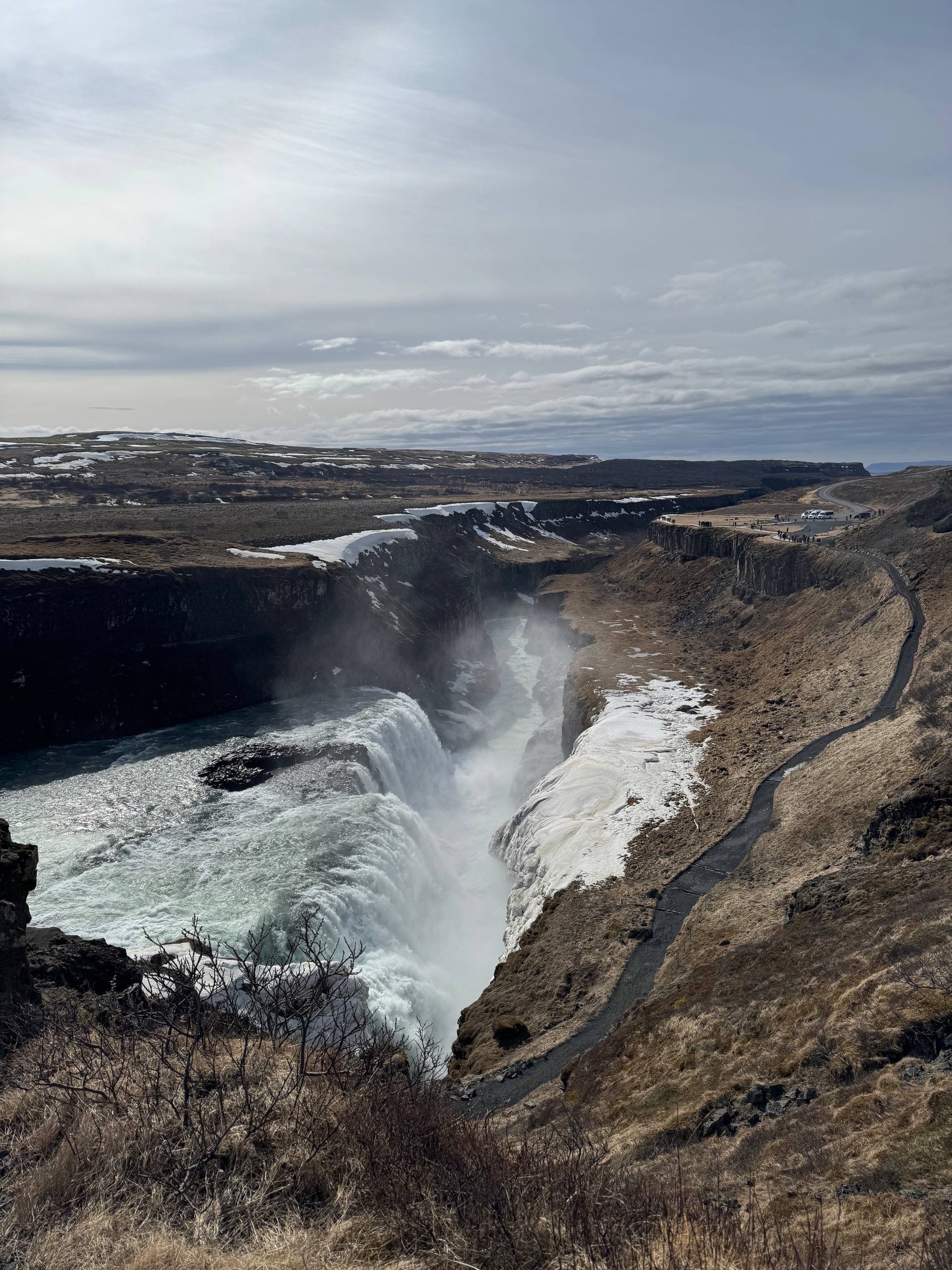 Gullfoss Waterfall cascading into a dramatic canyon with mist rising above the Hvítá River during a Day Trips From Reykjavik tour with our agency