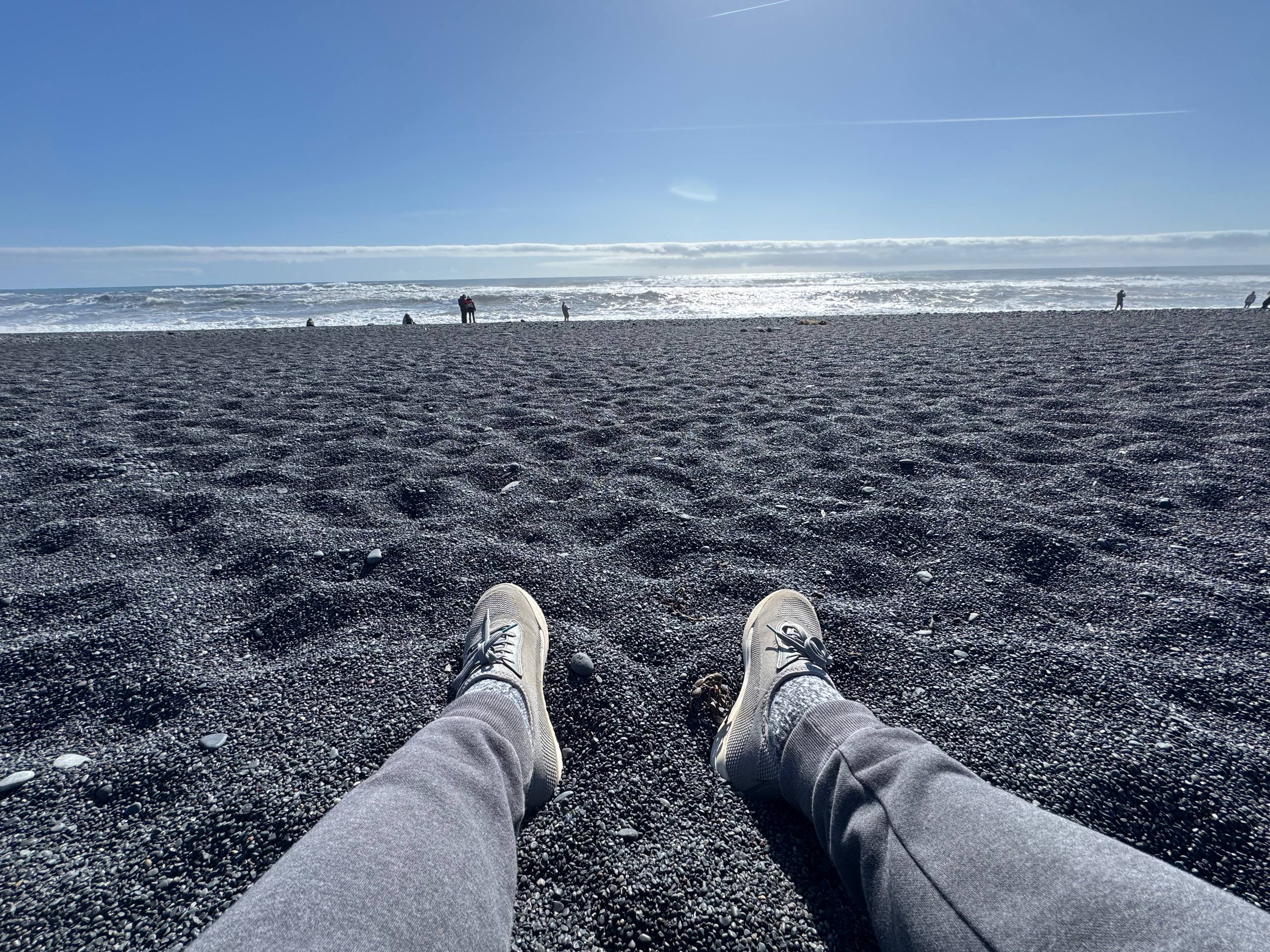 Reynisfjara Beach close-up showing smooth black pebbles and coastal scenery during a Day Trips From Reykjavik tour with our agency