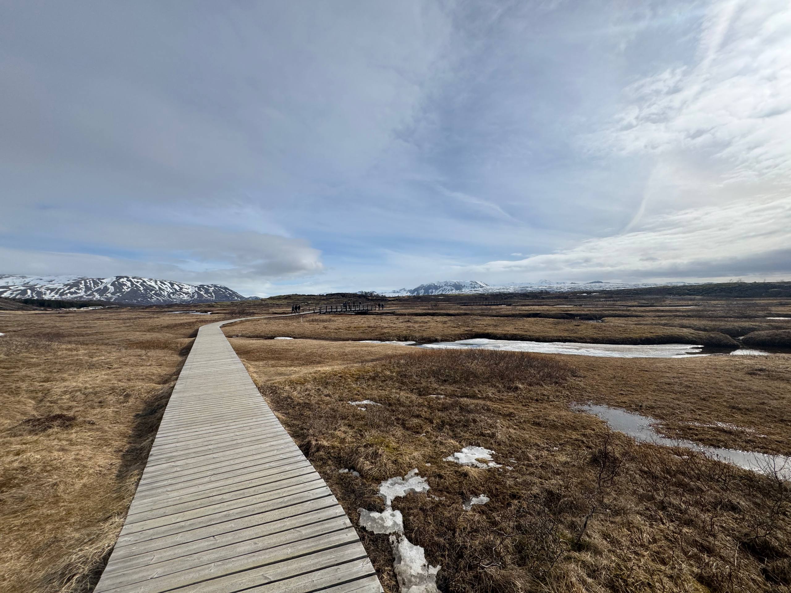 Panoramic view of Þingvellir National Park with trail pathway, open fields, and mountain backdrop during a Day Trips From Reykjavik journey with our agency