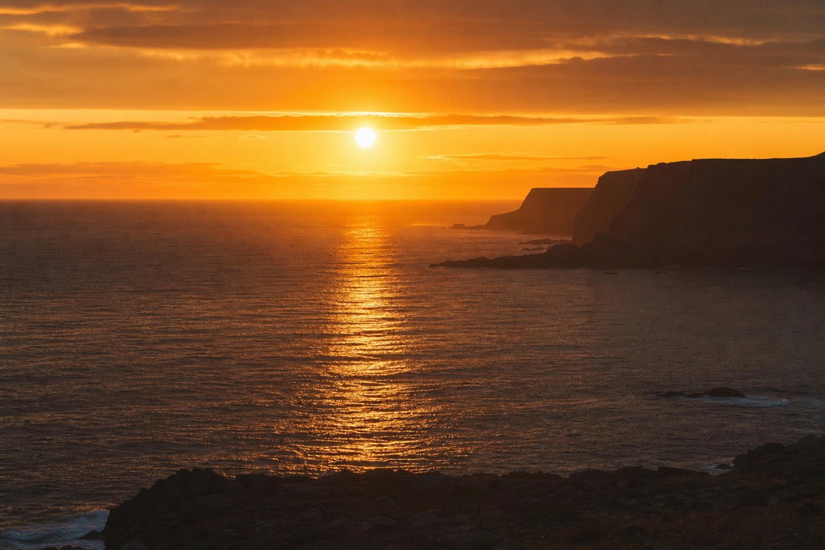 Low golden light across an Icelandic coastline near midnight in summer with the sun just above the horizon