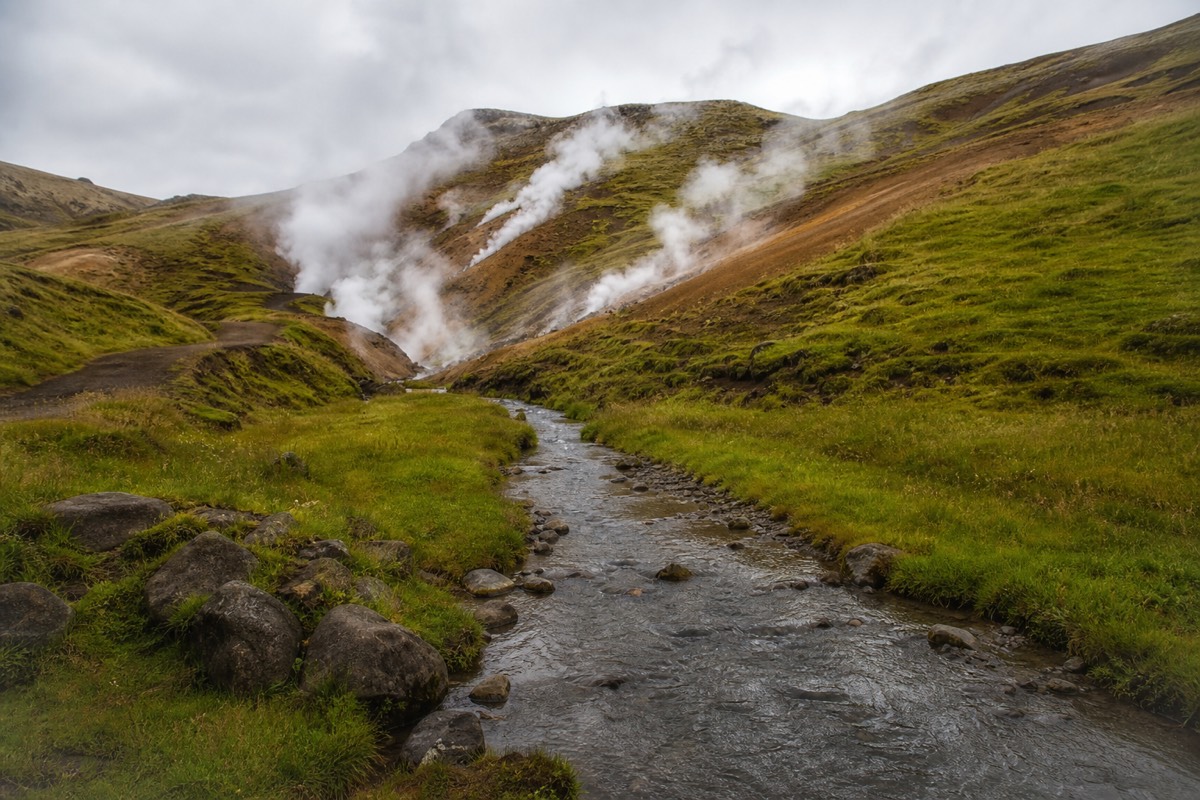 Steam drifting off the warm river running through the green Reykjadalur valley above Hveragerdi